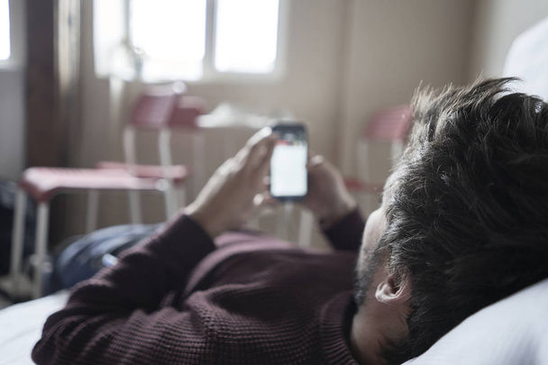 Hezký muž relaxuje ve své pohovce pomocí svého mobilu - Fotografie, Obrázek