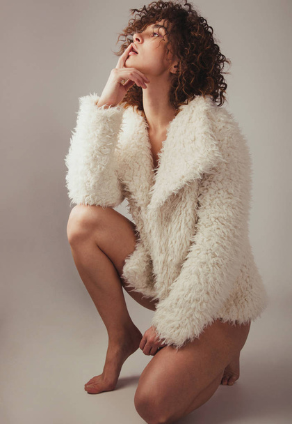 Beautiful woman in furry coat against gray background - 写真・画像
