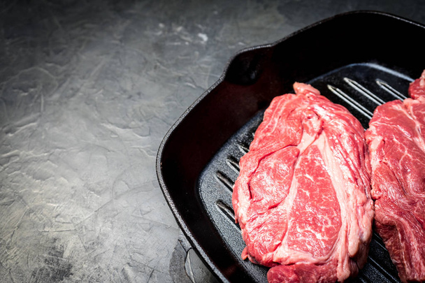 A raw marbled beef steak sits in a frying pan. - Foto, Bild