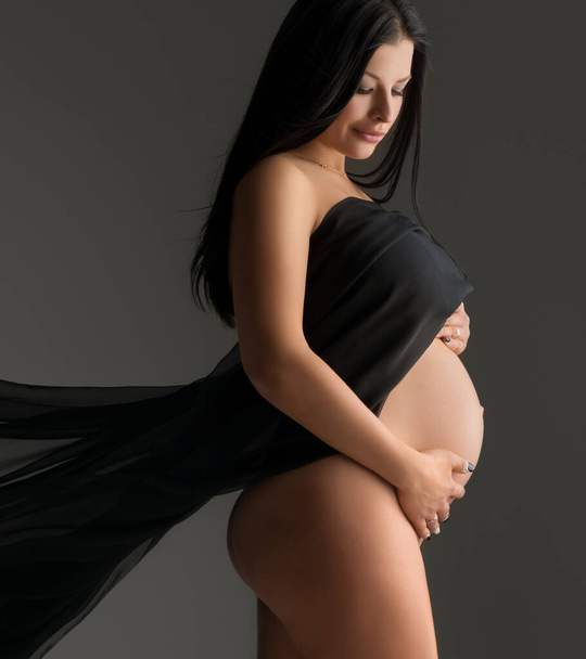 Elegant pregnant woman posing nude with cloth - Фото, изображение