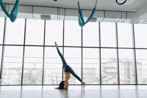 Młoda atrakcyjna dziewczyna robi ćwiczenia fitness z jogi na podłodze na tle panoramicznych okien - Zdjęcie, obraz