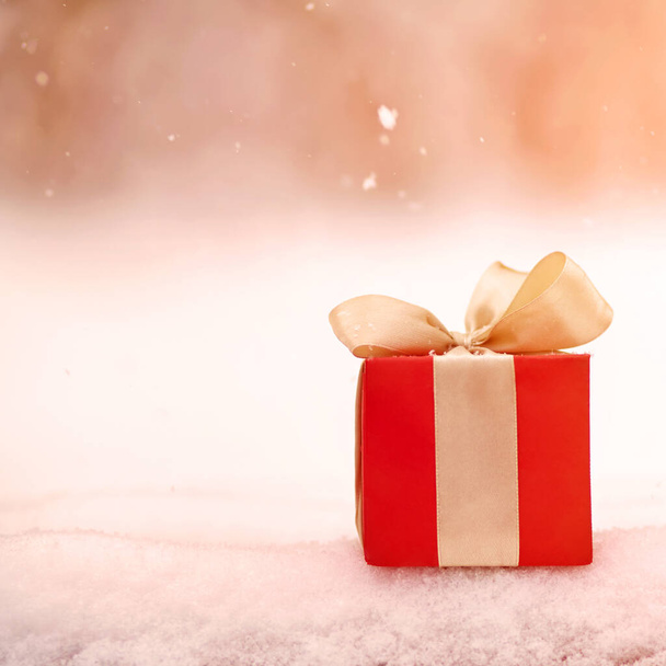κόκκινο χειμώνα Χριστούγεννα κουτί δώρου σε φόντο χιόνι σε εξωτερικούς χώρους. - Φωτογραφία, εικόνα