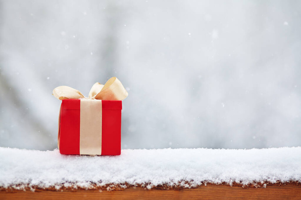 red winter Christmas gift box in snow background outdoors. - Φωτογραφία, εικόνα