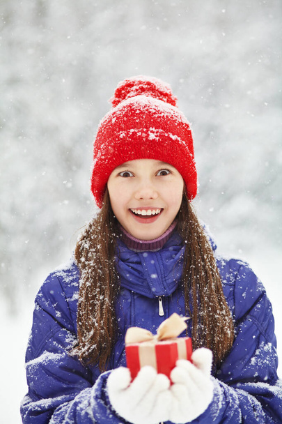 Teenager-Mädchen mit einem Geschenk in der Hand. Jugendlicher Winter im Freien - Foto, Bild