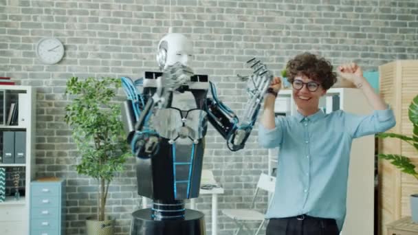 Slow motion of happy young woman dancing with robot in office having fun - Video