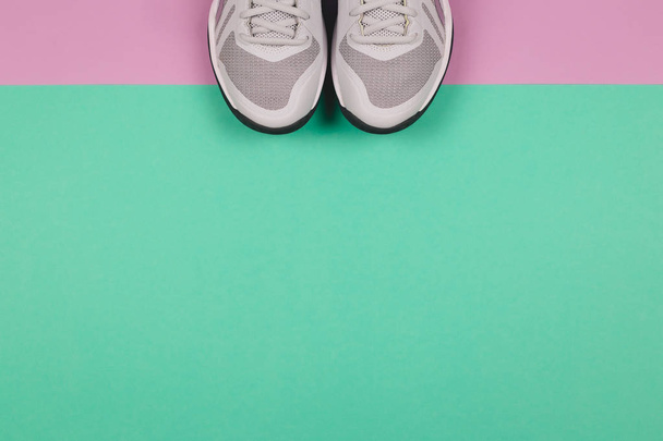 Grijze sneakers op de turquoise en violette achtergrond. Concept voor een gezonde levensstijl en dagelijkse training.   - Foto, afbeelding