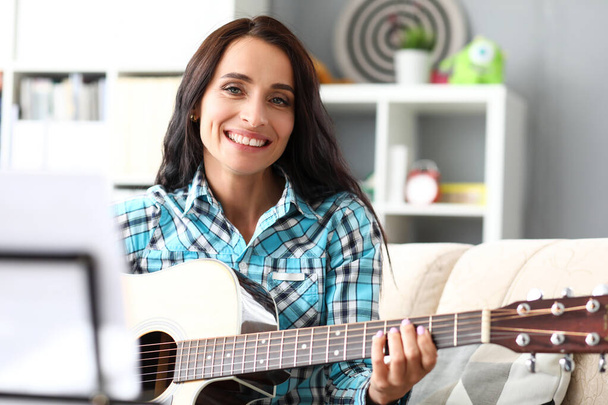 glimlachende brunette met gitaar - Foto, afbeelding