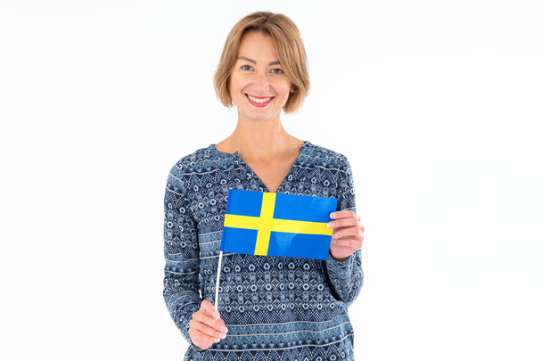 Beautiful smiling woman with flag of Sweden on the light studio background. - Valokuva, kuva