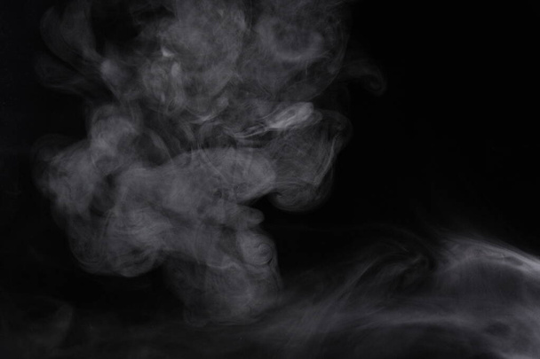 Puffs of smoke spread on a black background. - Фото, изображение