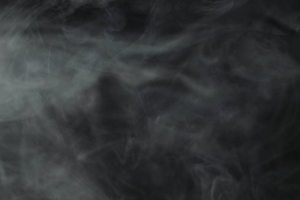 Puffs of smoke spread on a black background. - Foto, imagen