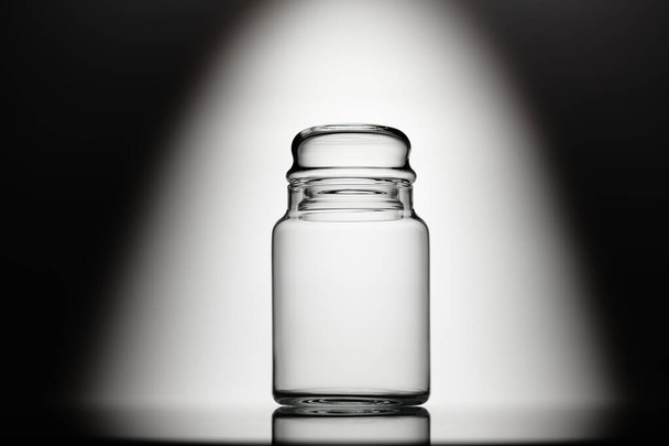 Lege glazen pot op een zwart-witte achtergrond - Foto, afbeelding