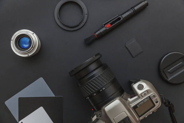 Photographer workplace with dslr camera system, camera cleaning kit, lens and camera accessory on dark black table background. Hobby travel photography concept Flat lay top view copy space - Photo, Image