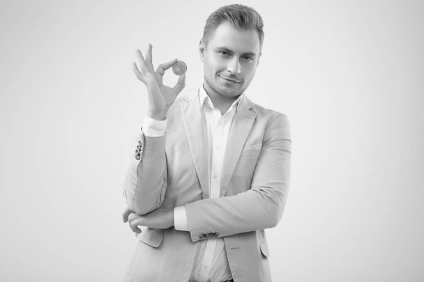 Handsome blonde man model in a fashion gray suit holds a Bitcoin - Photo, Image