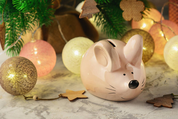 Het symbool van het nieuwe jaar. Piggy bank in de vorm van een muis. Kerstversiering, bloemenslinger en ballen - Foto, afbeelding