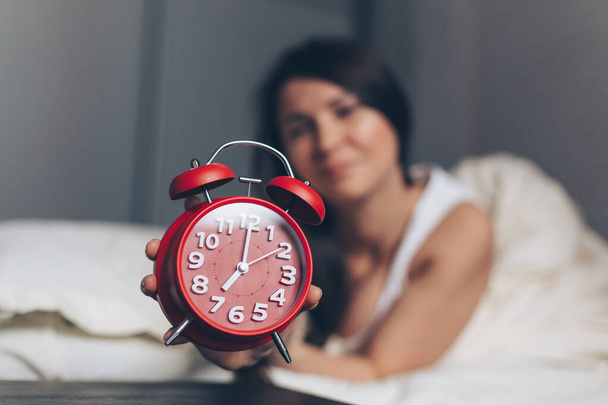 Smiling young caucasian woman showing alarm clock - Foto, Imagen