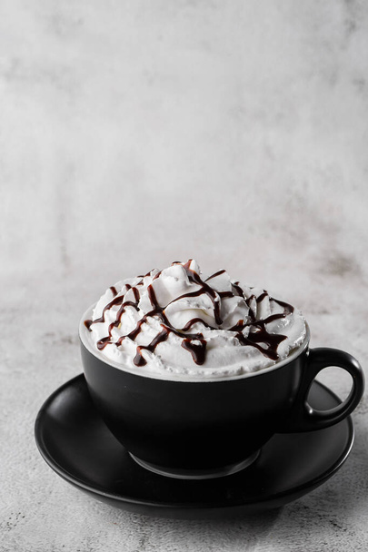 Coffe with whipped cream and chocolate topping. Iced frappuccino in dark cup isolated on bright marble background. Overhead view, copy space. Advertising for cafe menu. Coffee shop menu. Vertical phot - Photo, Image