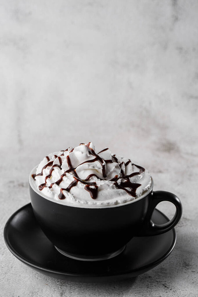 Coffe with whipped cream and chocolate topping. Iced frappuccino in dark cup isolated on bright marble background. Overhead view, copy space. Advertising for cafe menu. Coffee shop menu. Vertical phot - Photo, image