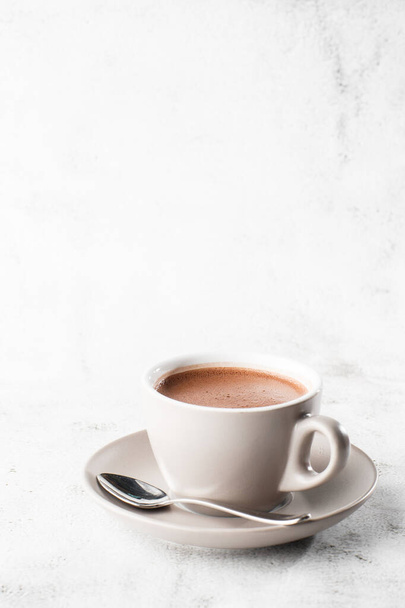 Cup of hot cocoa or hot chocolate or americano in white cup isolated on bright marble background. Overhead view, copy space. Advertising for cafe menu. Coffee shop menu. Vertical photo. traditional dr - Фото, зображення