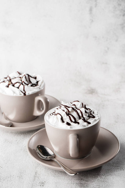 Two cups of coffee with whipped cream and chocolate topping. Iced frappuccino in white cup isolated on bright marble background. Overhead view, copy space. Advertising for cafe menu. Coffee shop menu. - Foto, Imagem