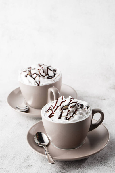 Two cups of coffee with whipped cream and chocolate topping. Iced frappuccino in white cup isolated on bright marble background. Overhead view, copy space. Advertising for cafe menu. Coffee shop menu. - Photo, image