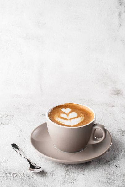 White cup of hot latte coffee with beautiful milk foam latte art texture isolated on bright marble background. Overhead view, copy space. Advertising for cafe menu. Coffee shop menu. Vertical photo. - Photo, Image