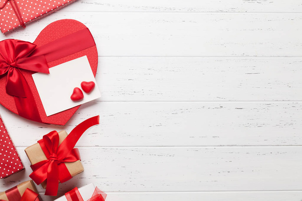 Carte de voeux Saint-Valentin avec coffrets cadeaux coeur sur fond bois. Vue de dessus avec espace pour vos salutations. Pose plate
 - Photo, image