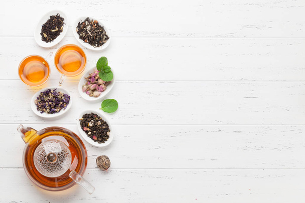 Různé bylinné a ovocné čaje a šálky na dřevěném stole. Pohled shora plochý s plochou kopie - Fotografie, Obrázek