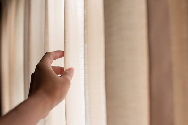 woman's hand is holding the curtains - Foto, Imagem