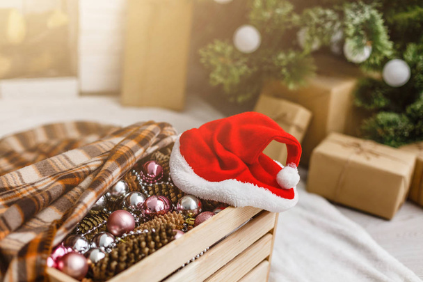 Karácsonyi ajándékok közelében a karácsonyfa és a Mikulás kalap - Fotó, kép