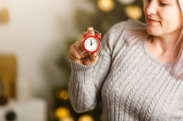 魅力的な女性ホールド赤レトロ目覚まし時計上のクリスマスバックグラウンド - 写真・画像