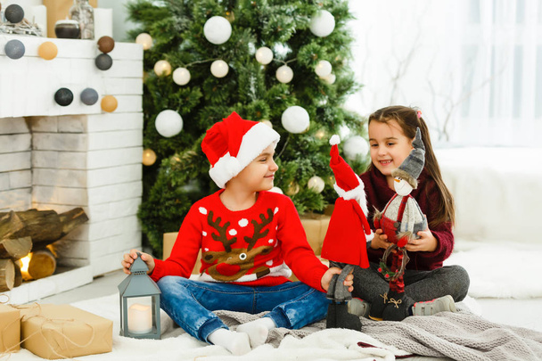 Bratr a sestra sedí blízko krásného vánočního stromečku doma - Fotografie, Obrázek