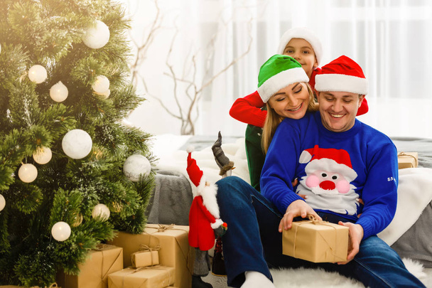 Η γοητευτική οικογένεια κάθεται κοντά στο χριστουγεννιάτικο δέντρο - Φωτογραφία, εικόνα