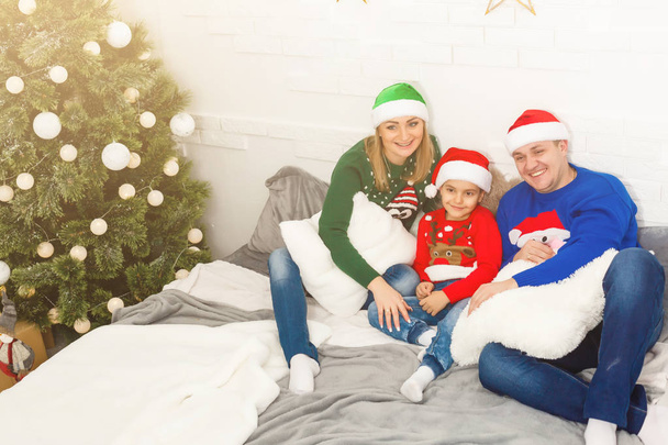 La encantadora familia sentada cerca del árbol de Navidad
 - Foto, imagen