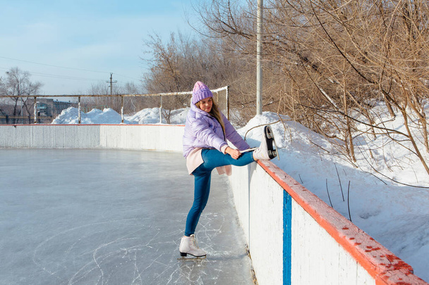 Lovely young woman riding ice skates on the ice rink. - Valokuva, kuva