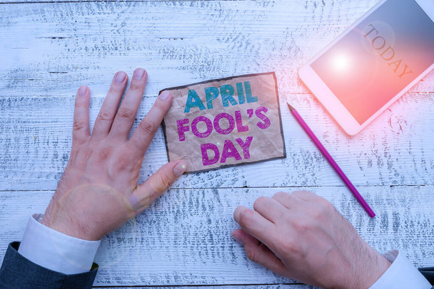 Text sign showing April Fool S Day. Conceptual photo Practical jokes humor pranks Celebration funny foolish Hand hold note paper near writing equipment and modern smartphone device. - Photo, Image
