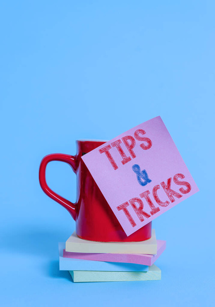 Conceptual hand writing showing Tips And Tricks. Business photo showcasing Steps Lifehacks Handy advice Recommendations Skills Coffee cup colored sticky note stacked pads plain background. - Photo, Image