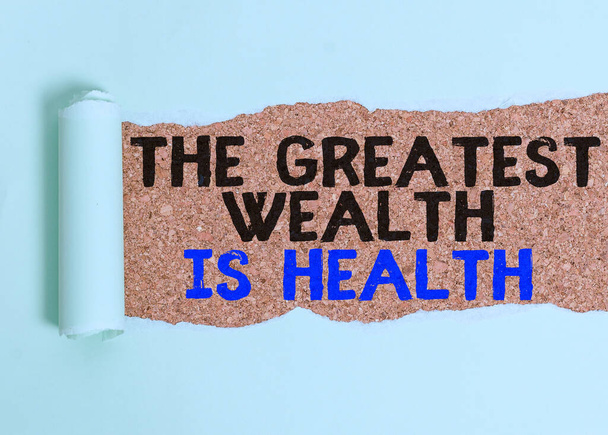 Writing note showing The Greatest Wealth Is Health. Business photo showcasing Many sacrifice their money just to be healthy Cardboard which is torn placed above a wooden classic table. - Fotoğraf, Görsel