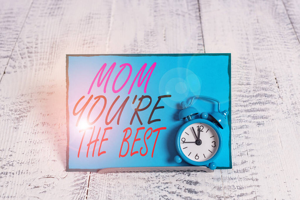お母さんにベストを示す概念的な手の書き込み.ビジネス写真紹介あなたのお母さんの愛の感情のための感謝賛辞目覚まし時計はノートペーパーの前でバッファ線の上に傾け. - 写真・画像