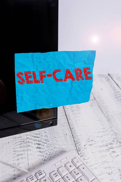 Texte manuscrit Self Care. Concept signifiant que la pratique de prendre des mesures pour améliorer sa propre santé Papier de notation collé à l'écran noir de l'ordinateur près du clavier blanc
. - Photo, image