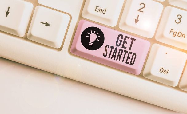 Text sign showing Get Started. Conceptual photo Begin an important period in one s is life or career Begin a task White pc keyboard with empty note paper above white background key copy space. - Photo, Image