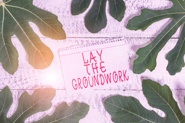 Szövegírási szöveg Lay The Groundwork. Üzleti koncepció az alapok vagy az alapítvány elkészítéséhez valamire Levelek a jegyzetfüzet körül egy klasszikus fából készült asztal felett, mint a háttér. - Fotó, kép