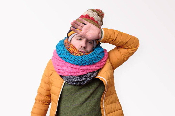 Tired caucasian funny man in several hats and scarfs in stressed - Photo, Image