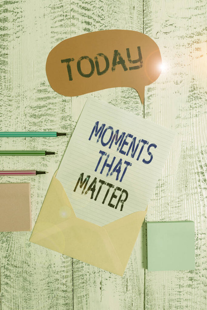 Writing note showing Moments That Matter. Business photo showcasing Meaningful positive happy memorable important times Envelop speech bubble paper sheet ballpoints notepads wooden background. - Photo, Image