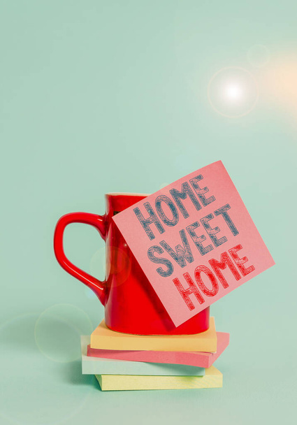 Fogalmi kézírás mutatja Home Sweet Home. Business photo showcasing In house finally Kényelmes érzés Relaxed Family time Coffee cup színes ragacsos jegyzet stacked párnák sima háttér. - Fotó, kép