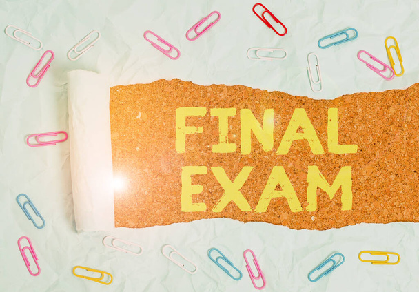 Text sign showing Final Exam. Conceptual photo test given to student at the end of a course of study or training Paper clip and torn cardboard placed above a wooden classic table backdrop. - Photo, Image