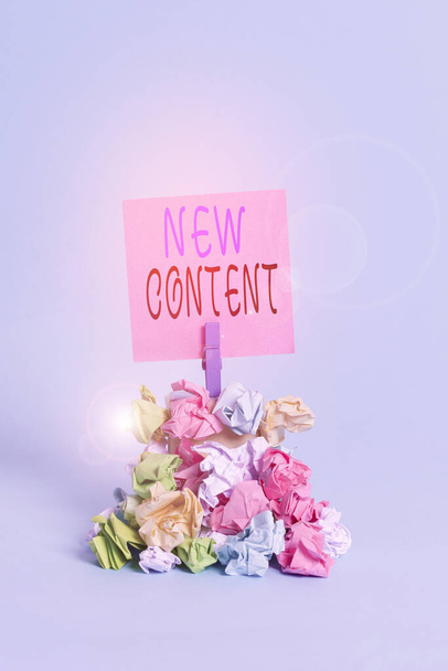 Text sign showing New Content. Conceptual photo fresh valuable and relevant information or context of a document Reminder pile colored crumpled paper clothespin reminder blue background. - Photo, Image