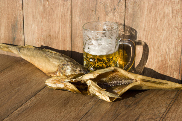 Γιορτή του Οκτόμπερφεστ. Καπνιστό ψάρι και ένα ποτήρι μπύρα. Κρύο καπνιστό περιστέρι σε σκούρο ρουστίκ φόντο. - Φωτογραφία, εικόνα