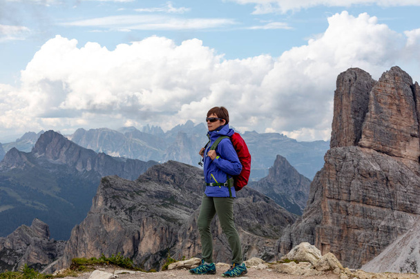 A girl in a blue jacket and with a backpack on a background of mountains. Italian Dolomites - Photo, Image
