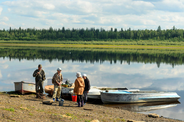 Grupa Yakut Azjatów czeka na łodzi na brzegu północnej rzeki Viluy.. - Zdjęcie, obraz