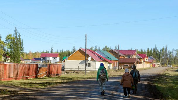 Yakut perheen miesten kanssa nainen ja yksi nuori tyttö reppu on tiellä uudella alueella omakotitalojen kylässä Suntar Yakutiassa
. - Valokuva, kuva